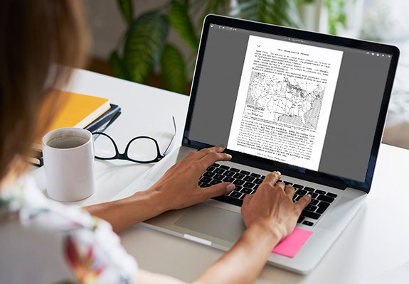 照片：使用笔记本电脑处理文档的女子