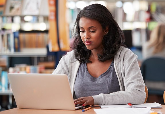 照片：在图书馆用笔记本电脑阅读的女子