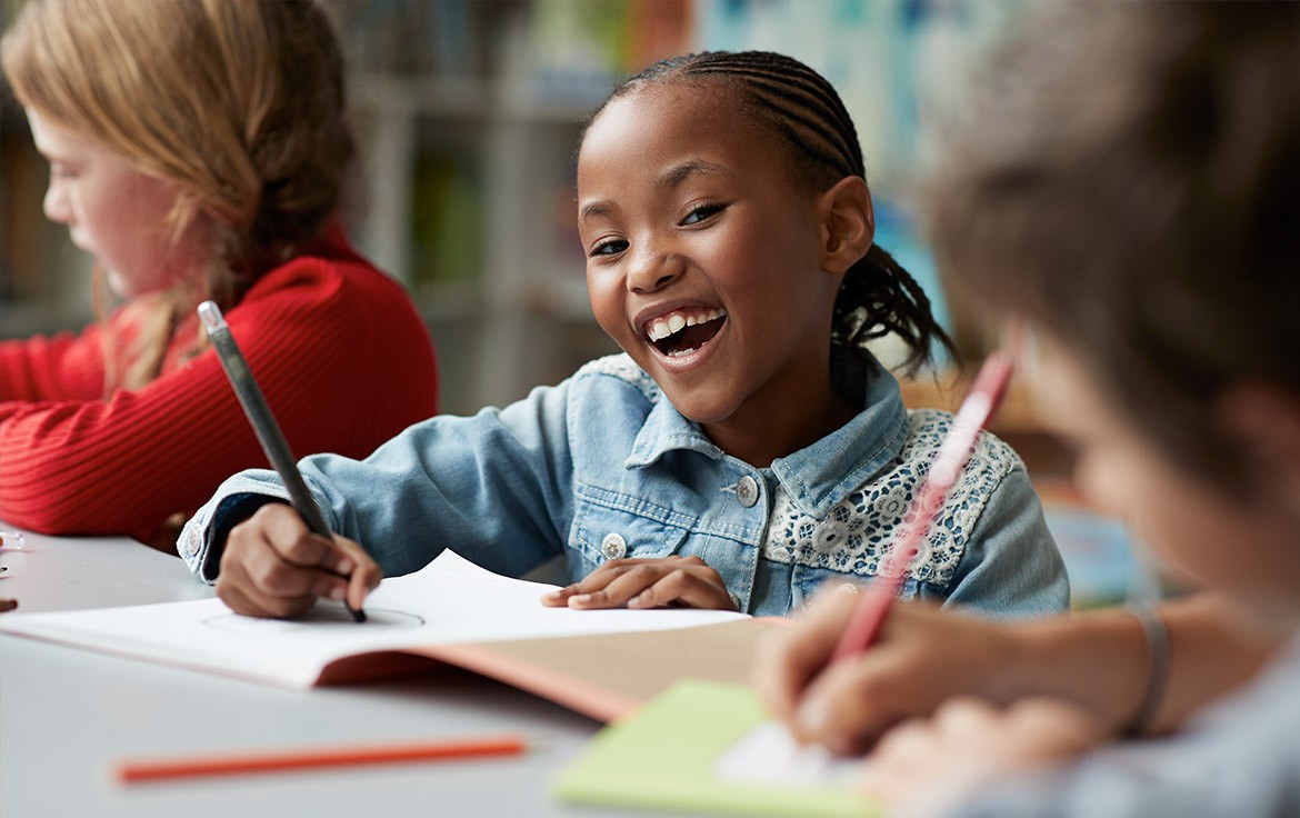   Kinderen werken geconcentreerd aan een opdracht in de klas, met schriften en potloden op tafel, omringd door een inspirerende leeromgeving.