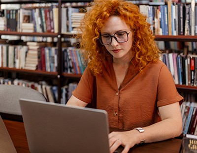 Bibliotecaria realizando catalogación en una computadora portátil