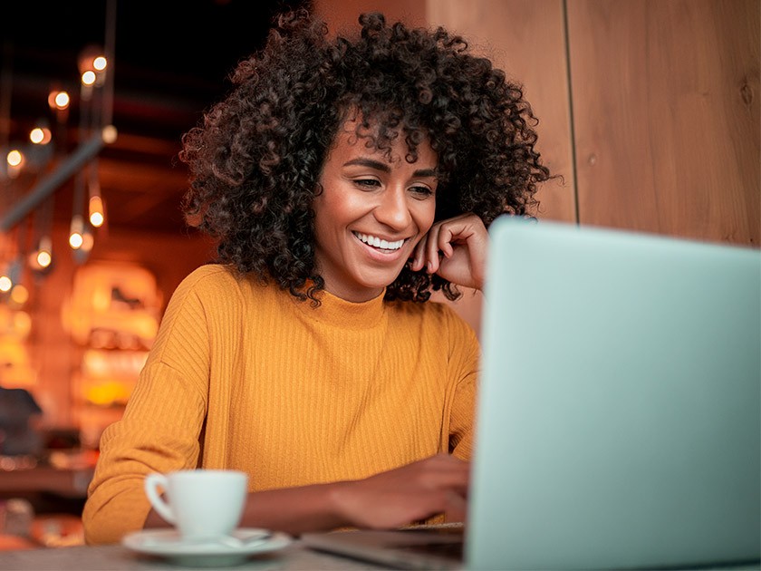 Photo: Femme lisant sur un portable dans un café