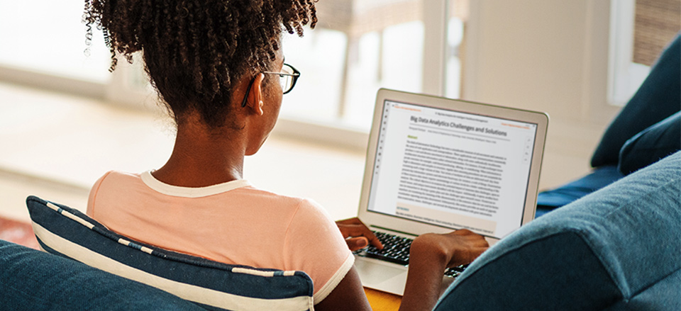 A library patron looking at a laptop displaying a scientific article